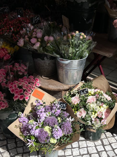 A vibrant display of freshly arranged flower bouquets primarily consisting of tulips in various colors. The tulips are grouped by color, including yellow, pink, red, orange, and purple, each densely p